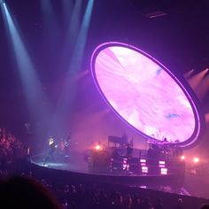 the stage is lit up with purple lights and people are standing in front of it