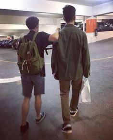 two young men are walking in an empty parking garage with their backs to each other