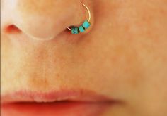 a woman's nose with a small turquoise bead on it