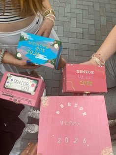 people are holding up pink boxes with writing on them that read senior year and the date