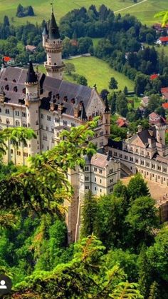 an aerial view of a castle in the middle of trees and hills with green grass