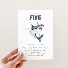 a person holding up a card with a shark on it's face and the words five