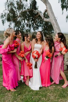 a group of women standing next to each other wearing pink dresses and holding bouquets