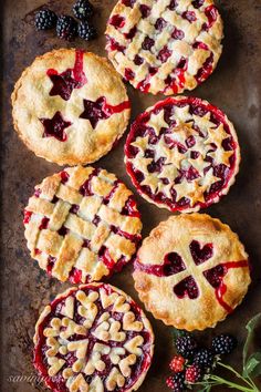 four berry pies on a baking sheet with fresh berries