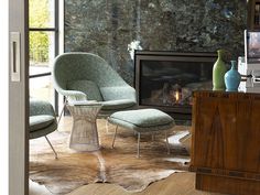 a living room scene with focus on the chair and footstool next to the fireplace