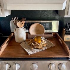 a wooden tray with utensils on top of an oven