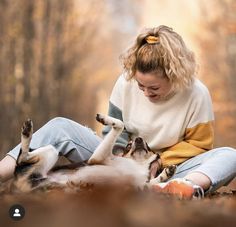 a woman is playing with her dog in the woods