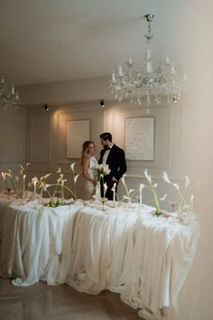 a bride and groom standing in front of a table with flowers on it