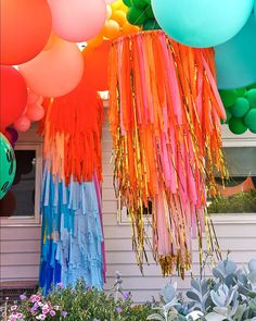 colorful balloons and streamers are hanging from the house's front porch, along with succulents