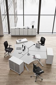 an office table with chairs and desks on it in front of large window overlooking water