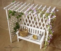 a white bench sitting under a trellis next to a basket with flowers on it