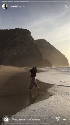 a person is walking on the beach near the water