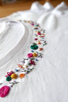 a white t - shirt with multicolored flowers embroidered on the front and back