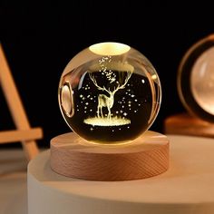 a glass ball with an image of a deer in the woods inside it on top of a wooden stand