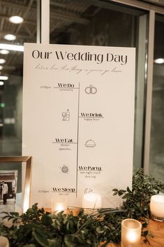 a sign that says our wedding day with candles and greenery in front of it