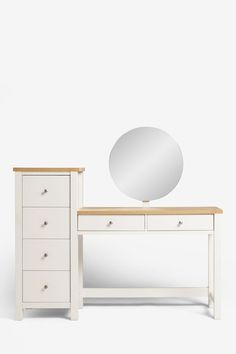 a white dresser and mirror next to each other in front of a white wall with a round mirror on it