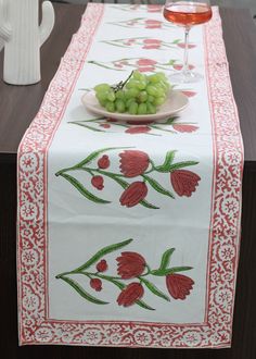 a table topped with a plate of grapes next to a glass of wine and a white vase