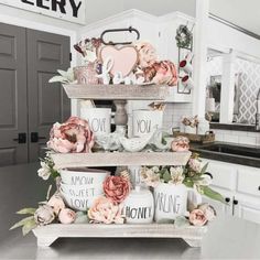 three tiered trays filled with coffee cups and flowers on top of a kitchen counter