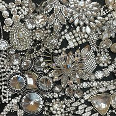 an assortment of brooches and jewels are displayed on a black cloth with white trim