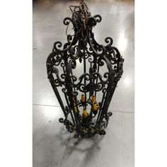 an ornate iron cage with candles on the bottom and yellow candles in it's center