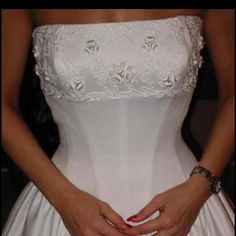 a woman in a white wedding dress is holding her hands on her waist and the bottom half of her skirt