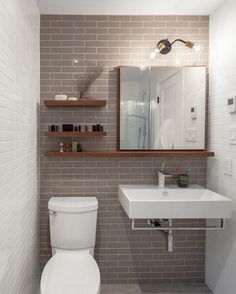 a white toilet sitting next to a sink in a bathroom under a mirror and lights