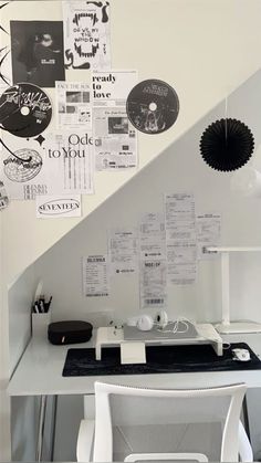 a white desk topped with a laptop computer next to a wall covered in posters and papers