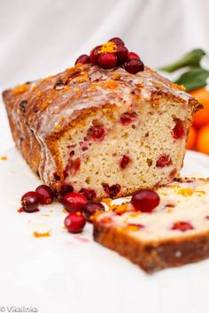 a loaf of cranberry orange bread on a white plate next to some fruit