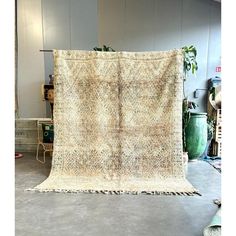 an old rug is sitting on the floor in front of a chair and potted plant