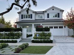 a white house with black shutters on the front and side windows, trimmed in boxwood