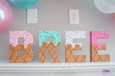 ice cream sign displayed on mantle in front of balloons and wall decor with letter's