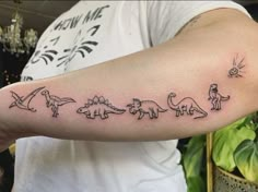 a man with a tattoo on his arm that has different types of dinosaurs in it