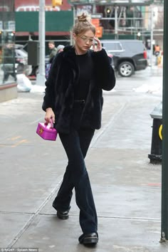 a woman is walking down the street talking on her cell phone and holding a purple purse