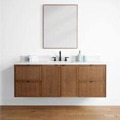 a bathroom vanity with two sinks and a mirror on the wall above it in a white room