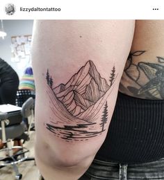 a woman's arm with a mountain and trees tattoo on the left side of her body