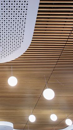 the ceiling is covered with round lights and wooden slats