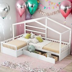 a white bed with drawers underneath it in a room filled with balloons and confetti