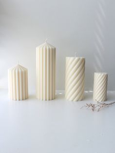 three white candles sitting next to each other on a table with one candle in the middle