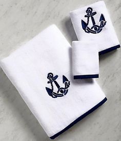 two white towels with an anchor on the front and blue trimmings are sitting on a marble surface