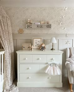 a baby's room with white furniture and wallpaper