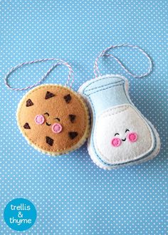 two felt ornaments are sitting on a blue tablecloth, one has a cookie and the other is a jar