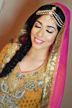 a woman in a yellow and pink outfit with braids on her head, smiling at the camera