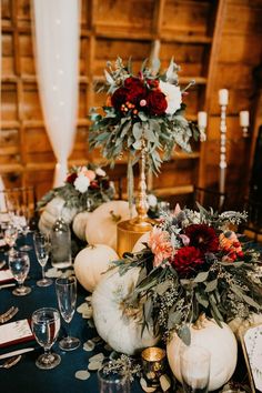 the table is set with pumpkins and flowers