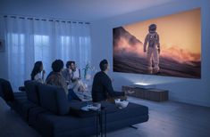 group of people sitting on couches in front of large screen television with astronaut image