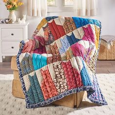 a multicolored quilt sitting on top of a wooden chair in front of a window