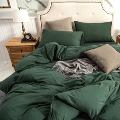 an unmade bed with green comforter and two pillows on top of the bed