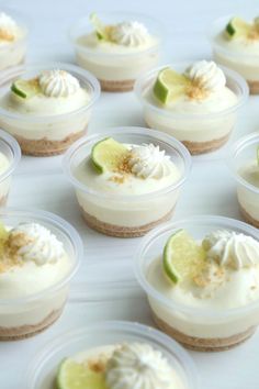 there are many small desserts in plastic cups on the table with lime wedges