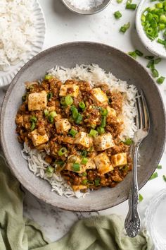 a bowl filled with tofu and rice on top of a table