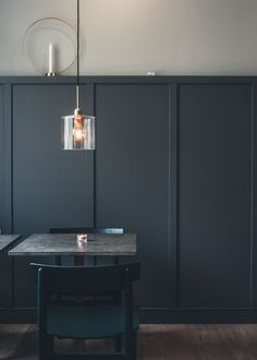 a dining room table with two chairs and a light fixture hanging from it's ceiling