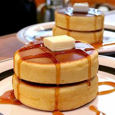 three pancakes covered in caramel syrup and butter on a white plate with sauce drizzled around them